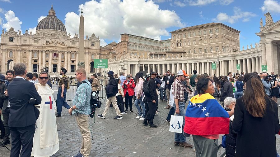 A la izquierda un religioso con el hábito trinitario y a la derecha una mujer envuelta en una bandera de Venezuela.