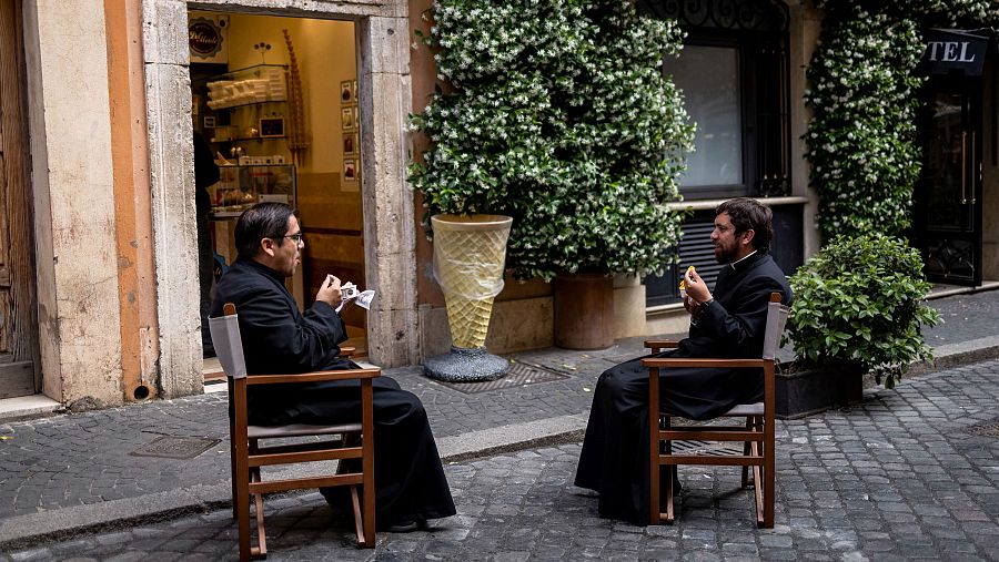 Dos sacerdotes charlan mientras comen un helado en la puerta de una famosa heladería romana.