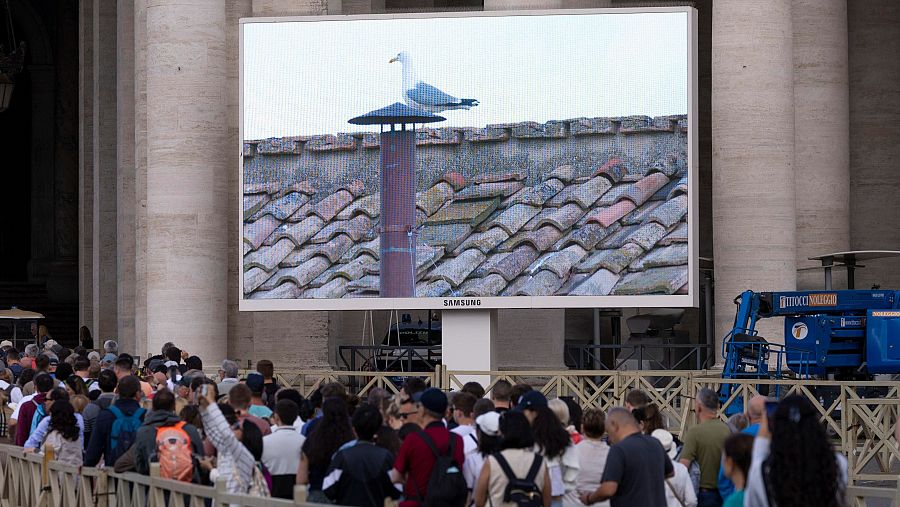 Una pantalla gigante en la Plaza de San Pedro muestra en directo la chimenea de la que está pendiente el mundo entero.