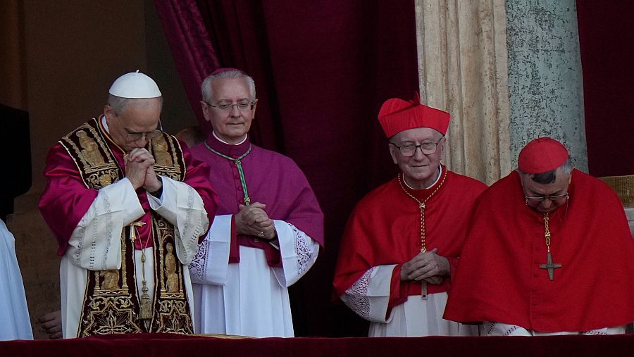 El papa León XIV, a la izquierda, reza en el balcón de la Basílica de San Pedro tras su elección