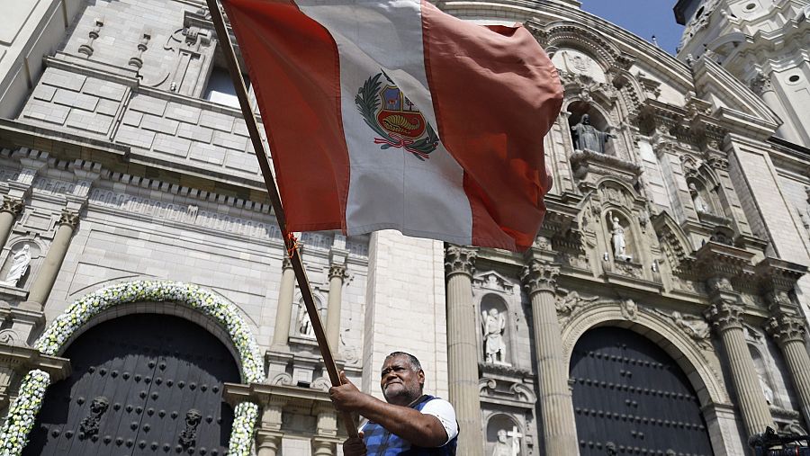 Un hombre sostiene una bandera de Perú frente a la Catedral de Lima tras la elección del papa