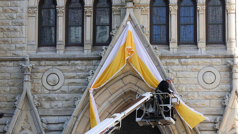 Un obrero cuelga banderolas papales en la entrada de la catedral de Chicago