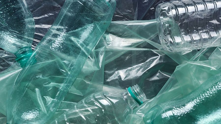 Botellas y bolsas de plástico, mayormente transparentes, apiladas, ilustrando la contaminación o la necesidad de reciclaje.