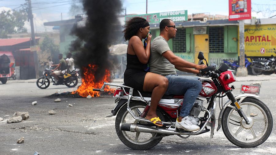 Un motociclista pasa junto a una barricada en llamas durante una protesta contra la violencia relacionada con las bandas y para exigir la dimisión del consejo presidencial de transición de Haití, en Puerto Príncipe