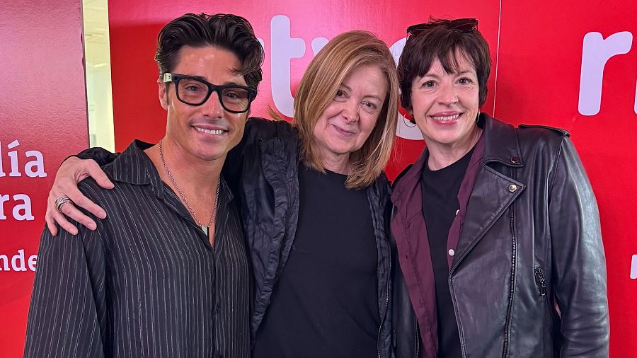 Ana Torrent y dos personas más posan en una foto con fondo rojo y grandes letras blancas.  Ella viste camiseta negra; él, camisa a rayas; y ella, chaqueta de cuero.
