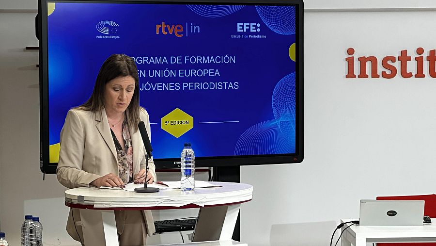 Presentación de la 5ª edición de un programa de formación para jóvenes periodistas en la Unión Europea. La directora de RTVE Instituto habla desde un atril con una pantalla mostrando los logotipos del Parlamento Europeo, RTVE y EFE.