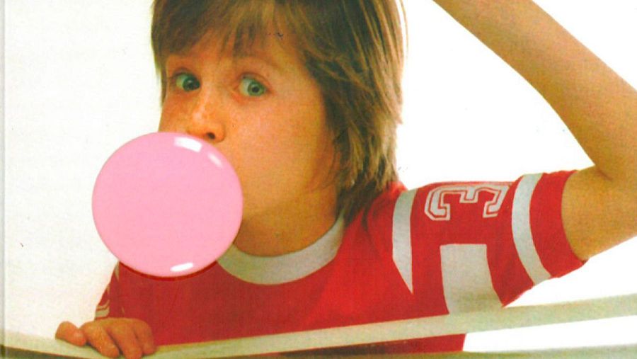 Niño con camiseta roja infla un gran chicle rosa; fondo blanco; texto menciona la 'memoria de delfín'.