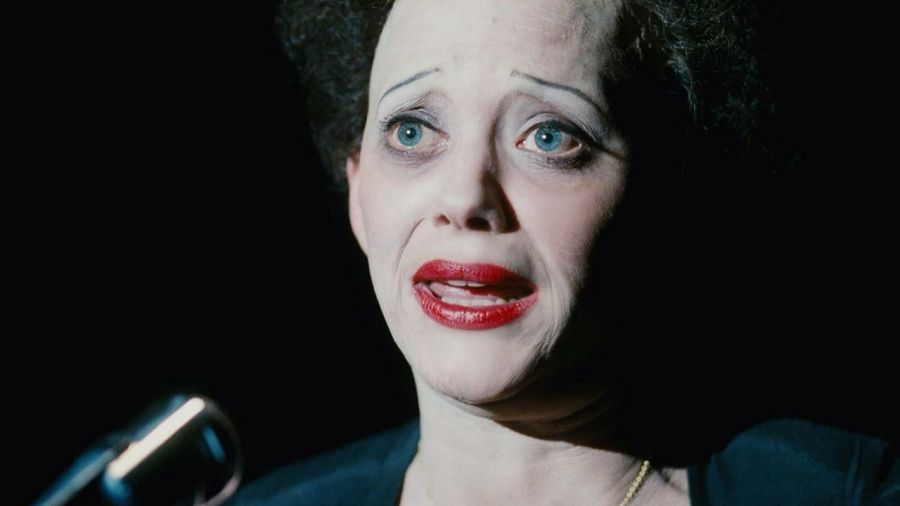 Marion Cotillard como Édith Piaf en 'La vie en rose'. Primer plano con iluminación dramática, rostro con expresión intensa y micrófono visible.
