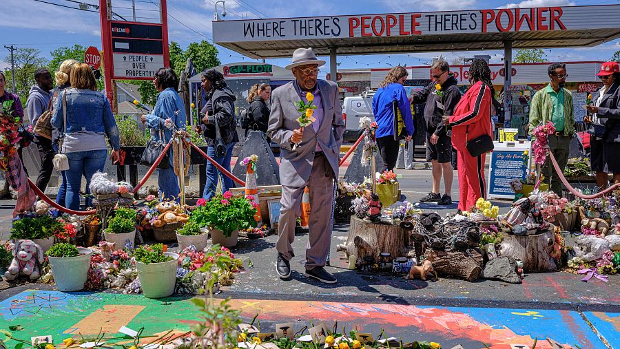 Miembros de la comunidad y familiares de Floyd se reúnen alrededor de un mural de George Floyd en George Floyd Square para dejar rosas amarillas y fotos en su memoria
