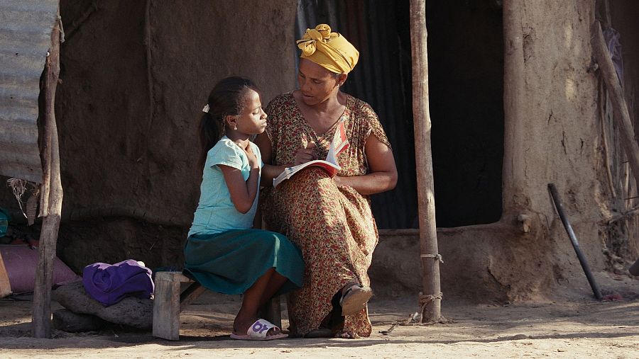 Workinesh y su hija leen un libro en su corral de la aldea de Dibdibbe.