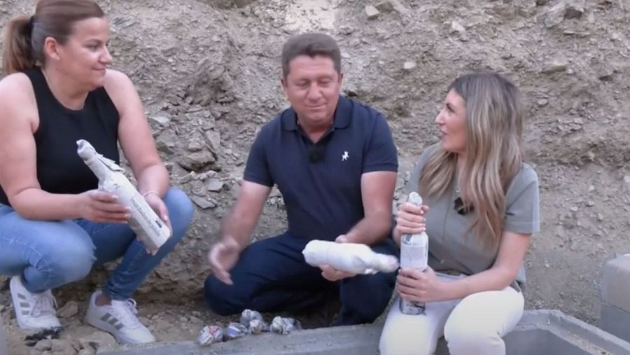 Arqueólogos examinan botellas envueltas en una excavación.  Dos mujeres y un hombre manipulan con cuidado los objetos desenterrados en un terreno rocoso.