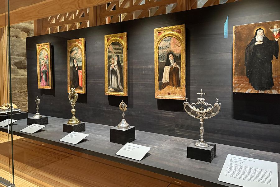 Vitrina con relicarios y pinturas religiosas (medievales/renacentistas) enmarcadas en dorado; objetos de plata, incluyendo posibles custodias; cartelas informativas ilegibles.