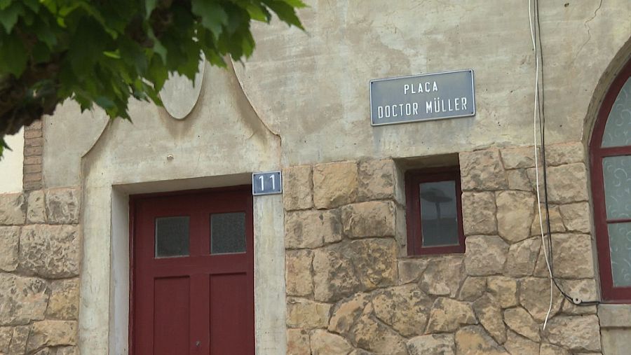 Edificio de piedra rústica con puerta roja de cuatro paneles, placa con el número 11 y otra placa que indica 
