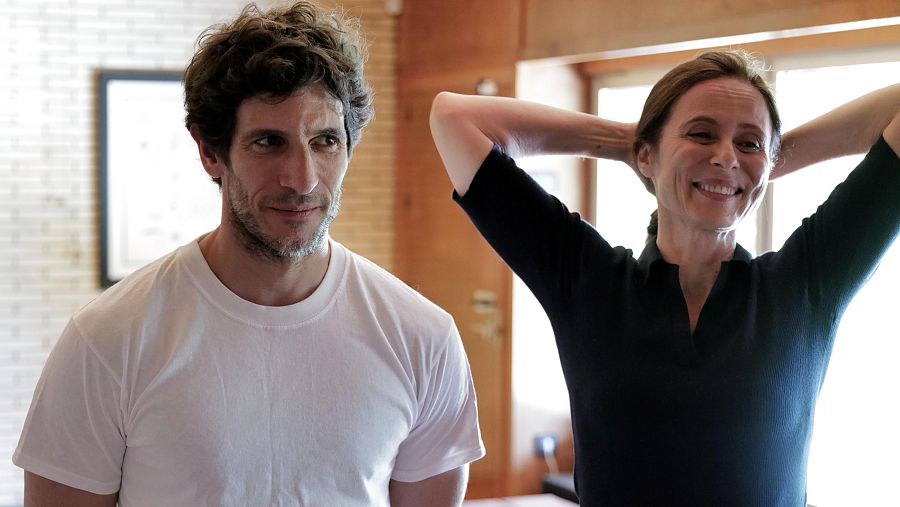 Quim Gutiérrez y Aitana Sánchez-Gijón, en un rodaje, descansan en un interior de ladrillo visto y madera. Él lleva camiseta blanca; ella, ropa oscura.