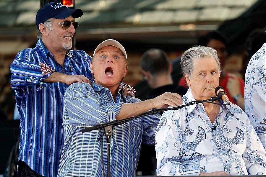Tres miembros de The Beach Boys, en un concierto de 2012 en Nueva York.  Se muestran en escena, con ropa informal y mostrando interacción entre ellos.