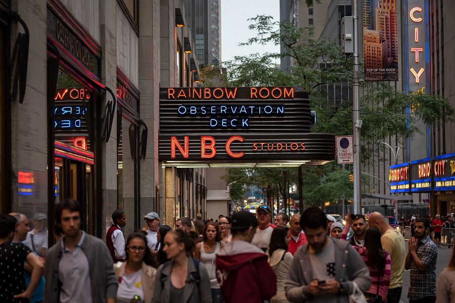 Entrada nocturna a NBC Studios en Nueva York, con letreros luminosos de 