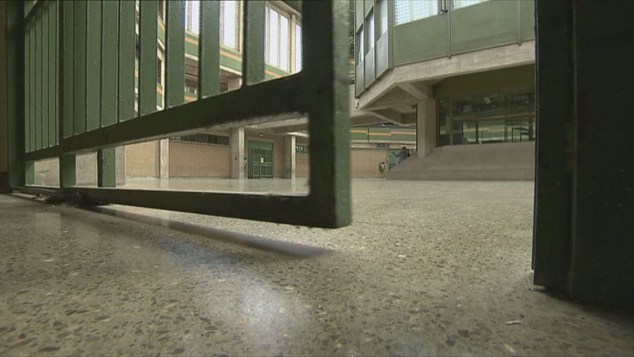 Imagen desde una celda mostrando un patio y un edificio a través de una reja verde.  Se ve una figura humana pequeña al fondo. Texto: 'PRESOS 10 Repor'.