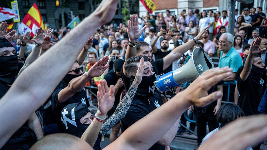 Varias personas hacen el saludo fascista durante la concentración en la sede del PSOE