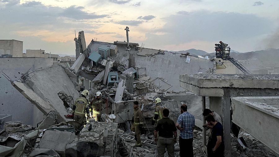 Personas y equipos de primeros auxilios se reúnen en lo alto de un edificio alcanzado por un ataque israelí en Teherán