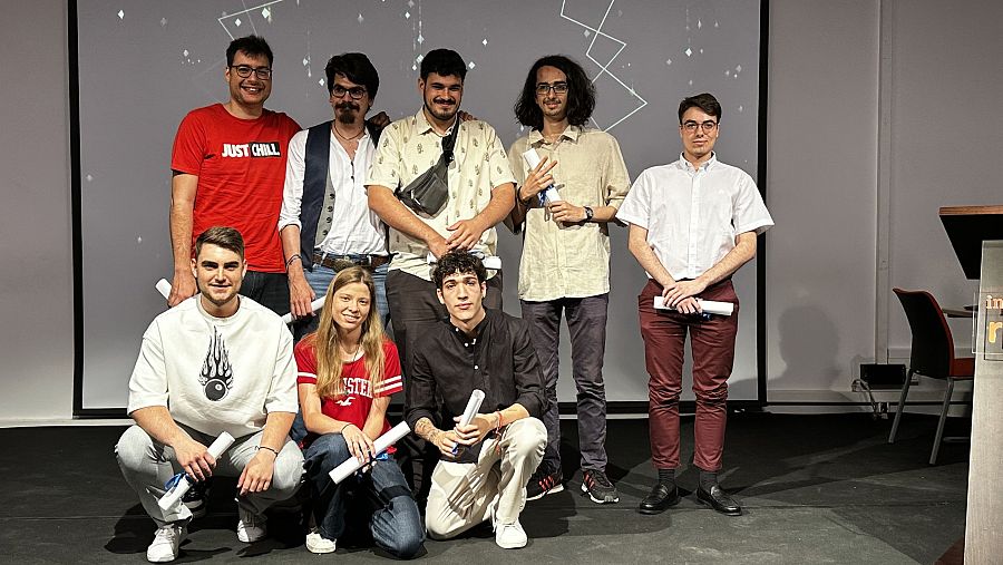 Graduados de Animación posan con sus diplomas en una sala de conferencias.  Ambiente festivo. Ropa informal.