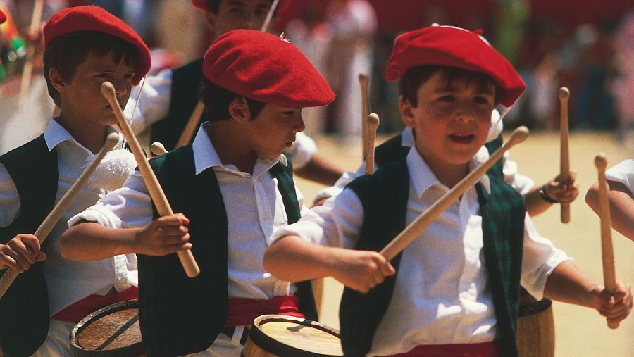 Niños con trajes tradicionales tocando tambores en las fiestas de San Fermín