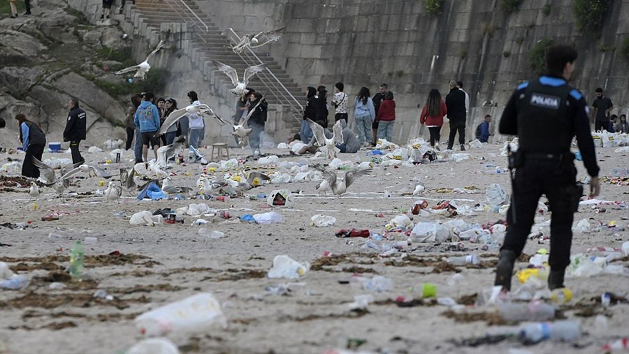 Un agente de Policía Local entre los restos de basura en la playa de Orzán en una imagen de archivo de 2022