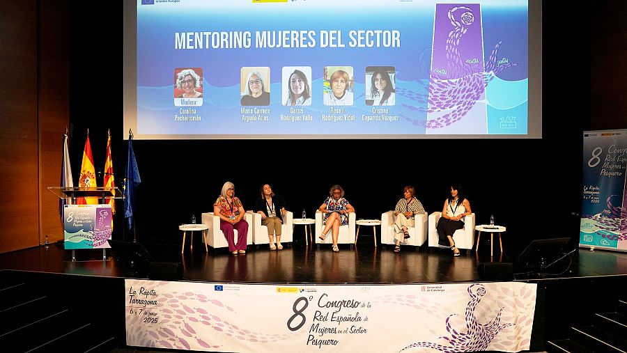 Mesa redonda con cuatro mujeres en el 8º Congreso de la Red Española de Mujeres en el Sector Pesquero.  Presentación en pantalla sobre mentoring con fotos de mentoras.