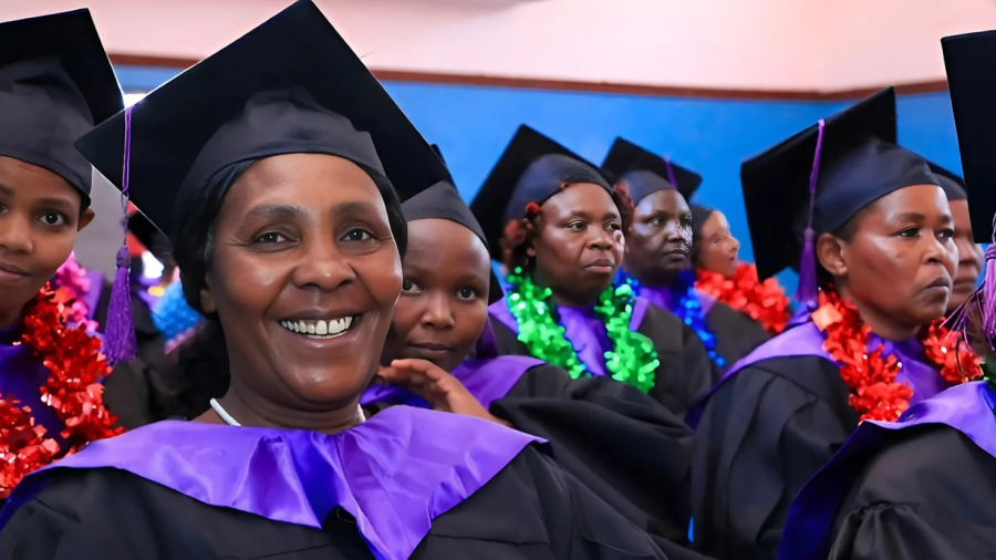Mujeres keniatas, vestidas con birretes y togas, celebran su graduación con guirnaldas de colores.  Sus rostros expresan felicidad y orgullo por el logro alcanzado.