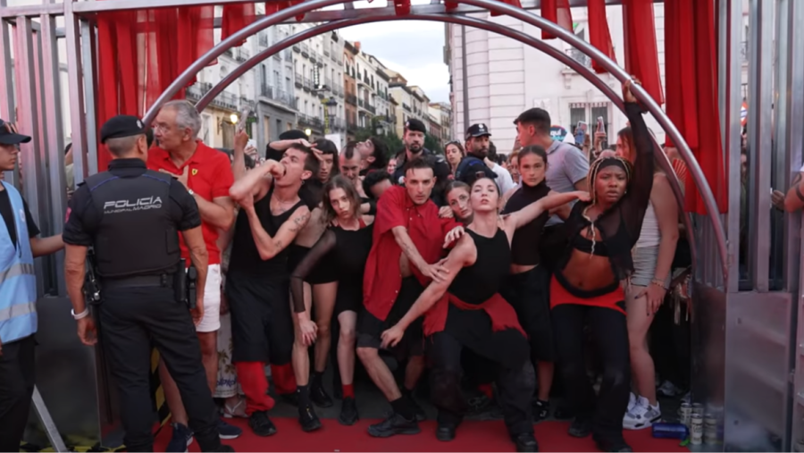 Actuación de flamenco en la Puerta del Sol, Madrid. Bailaores y cantaores con trajes rojos y negros en un escenario improvisado, rodeados de público y policía.