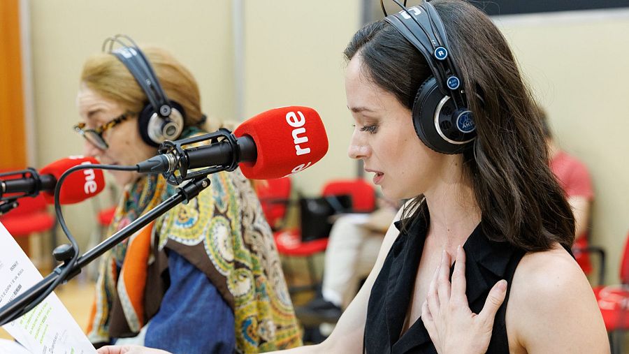 Dos mujeres ensayan en un estudio de radio 'rne', con auriculares y papeles, aparentemente para una obra radiofónica.
