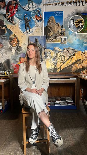 Patricia Toledo, encargada de la libería Desnivel junto a el mural de la élite alpinista