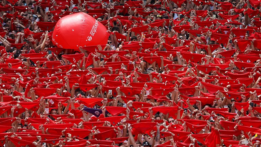 Una multitud celebra el inicio de los Sanfermines en la Plaza Consistorial con el Chupinazo desde el balcón del ayuntamiento de Pamplona, este domingo.
