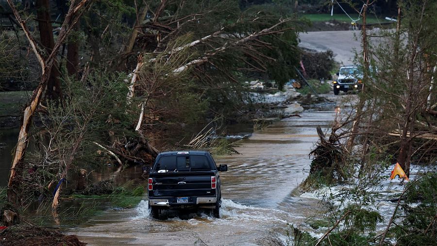 Un vehículo circula por una carretera inundada, tras una crecida repentina, en Hunt, Texas