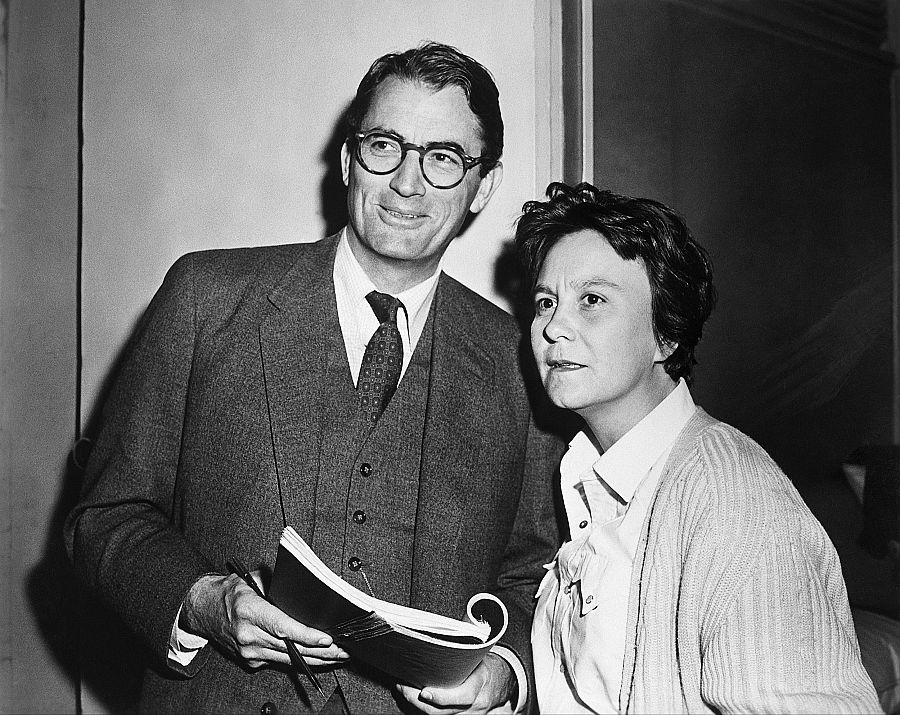 Gregory Peck y Harper Lee en el set de 'Matar a un ruiseñor' (1962).  Él, en traje y gafas, sostiene un libro; ella, con camisa blanca y cárdigan, lo mira con atención.