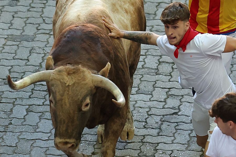 San Fermín 2025: un mozo corre junto a uno de los toros de la ganadería Victoriano del Río