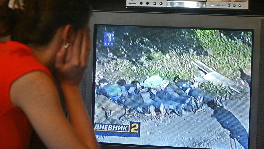 Una mujer ve un video en televisión que muestra ejecuciones de musulmanes bosnios de Srebrenica