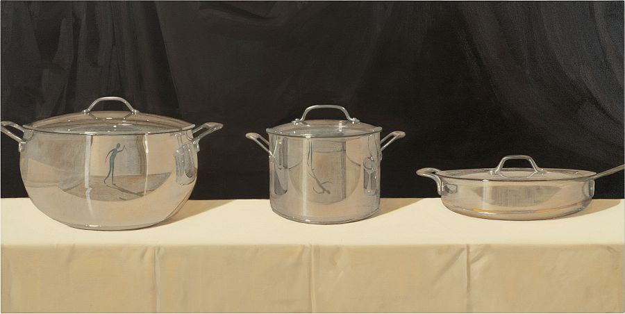 Tres ollas de acero inoxidable con tapas, de diferentes tamaños, sobre un mantel crema.  Reflejo de una figura humana visible en las superficies brillantes.