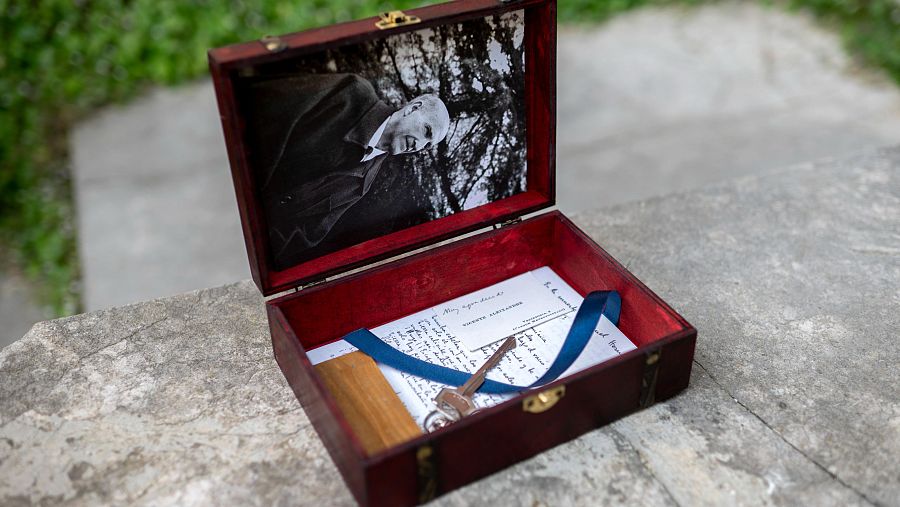 Caja abierta con foto de Vicente Aleixandre, documento manuscrito o mecanografiado con cinta azul, llave y pieza de madera.