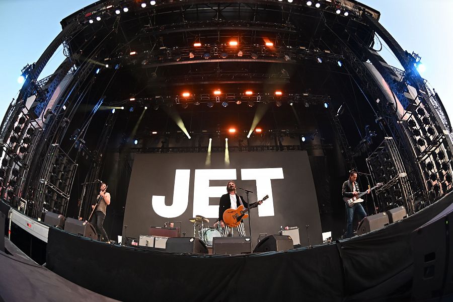 Concierto de Jet en Madrid. Imagen con distorsión ojo de pez mostrando a la banda en el escenario tocando instrumentos, con el nombre 