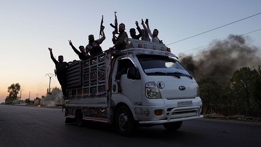 Combatientes beduinos montan en un vehículo por una calle