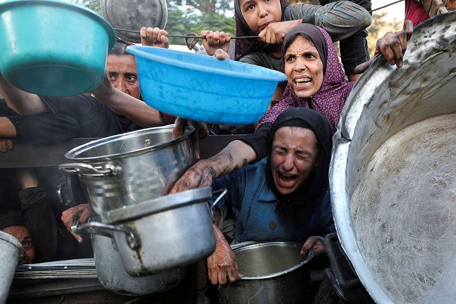 Palestinos reaccionan mientras piden comida en una cocina de caridad, en medio de una crisis de hambre, en la ciudad de Gaza