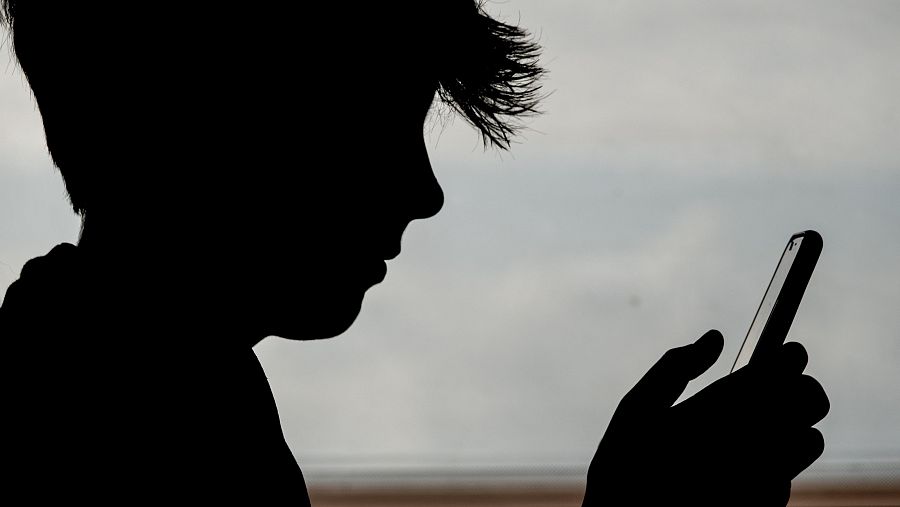 Silueta de perfil de un joven usando un teléfono, contra un fondo claro.  Postura que indica interacción con el dispositivo.