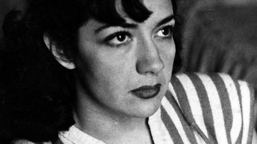 Retrato en blanco y negro de Ana María Matute, con el pelo oscuro y raya al lado; expresión seria y pensativa; viste jersey de rayas horizontales.