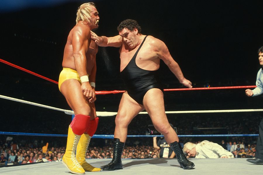 Combate de lucha libre: Hulk Hogan, en amarillo, recibe un golpe.  El ring, con cuerdas rojas, blancas y azules, y un árbitro son visibles.