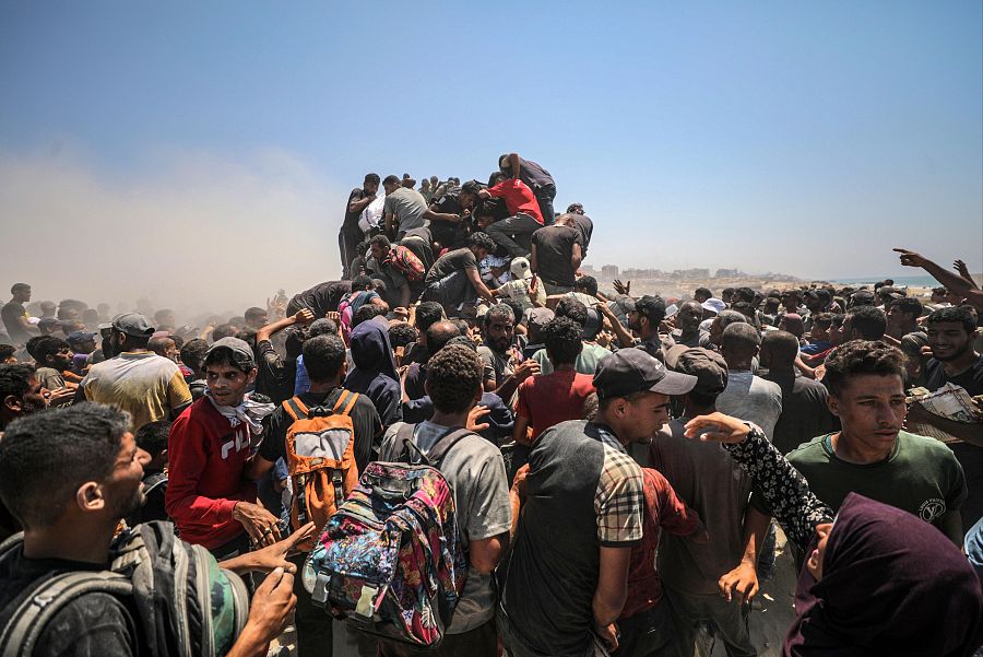 Palestinos desplazados se abalanzan sobre un camión de ayuda humanitaria cerca de un punto de distribución de alimentos en Zikim, al norte de la Franja de Gaza