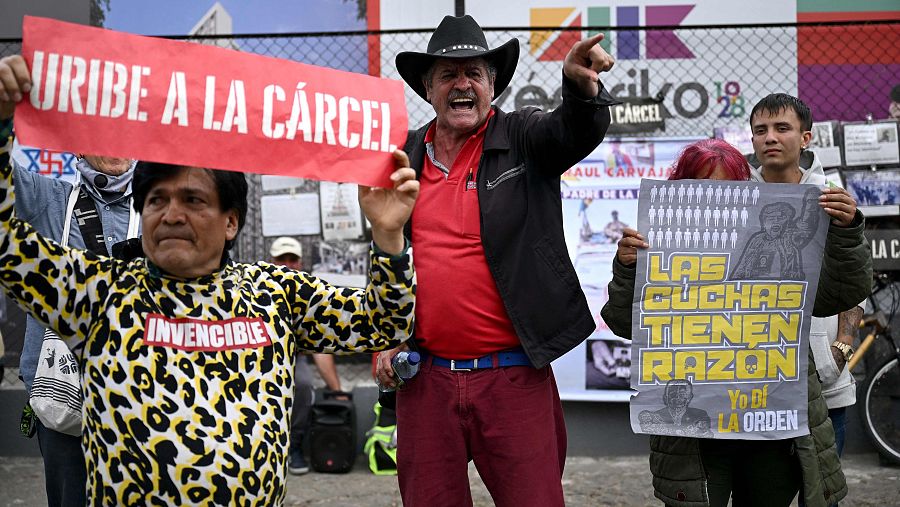 Un hombre grita entre personas que sostienen carteles contra el expresidente colombiano Álvaro Uribe en Bogotá, el 28 de julio de 2025.