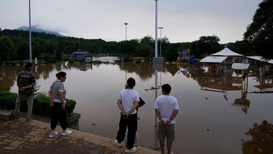 Personas observan un parque inundado tras fuertes lluvias en el distrito de Miyun, en las afueras de Pekín,