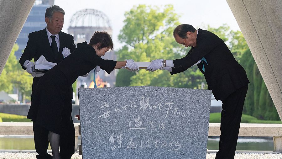 El alcalde de la ciudad de Hiroshima, Kazumi Matsui, y una representante de las familias de las víctimas colocan una lista de las víctimas de la bomba atómica en el cenotafio
