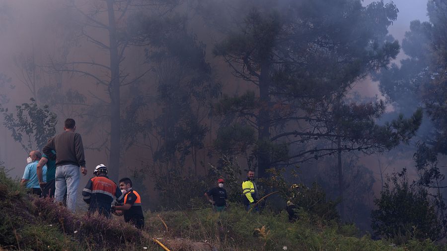 Varias personas tratan de extinguir el fuego, a 5 de agosto de 2025, en Ponteceso, A Coruña