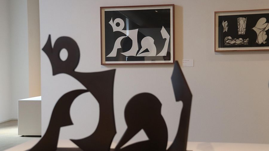 Una escultura de Marcel Martí en primer terme amb un collage que representa la mateixa escultura exposada al museu Can Mario de Palafrugell